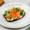 Фото к позиции меню Брускетта со слабосоленым лососем, сметаной, зеленым маслом и листьями салата на бородинском хлебе