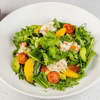 Большой салат с камчатским крабом, красной икрой, авокадо, листьями салата, апельсинами и соусом