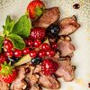 Фото к позиции меню Подкопченая утиная грудка, запеченая в медовом соусе с ягодами малины, ежевики, клубники и винoградом