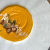 Фото к позиции меню Фирменный морковно-сливочный крем-суп с тигровыми креветками и лепестками миндаля