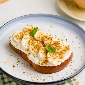 Бриошь с бананом, сливочным соусом и дроблёнными фисташками