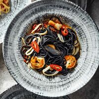 Черные спагетти с морепродуктами в соусе том ям