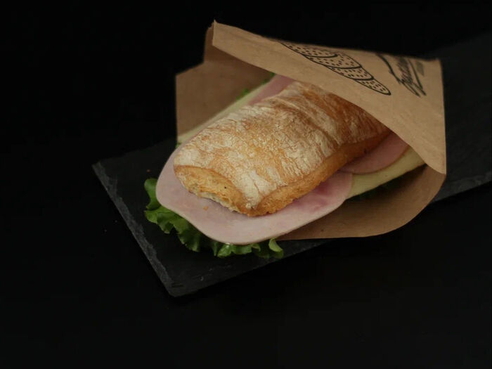 Сэндвич с ветчиной, сыром и зеленью в булочке панини